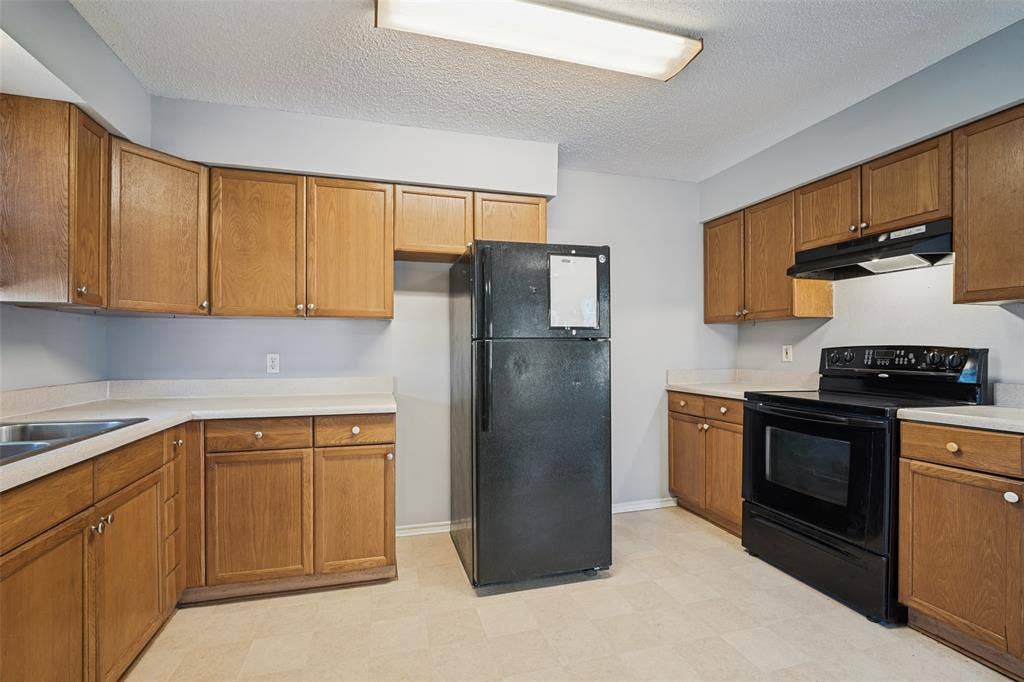 415 S Bell Street, Royse City, TX 75189 Kitchen featuring shaker-style wood cabinetry, solid-surface countertops, integrated range hood, and flush-mount linear ceiling lighting