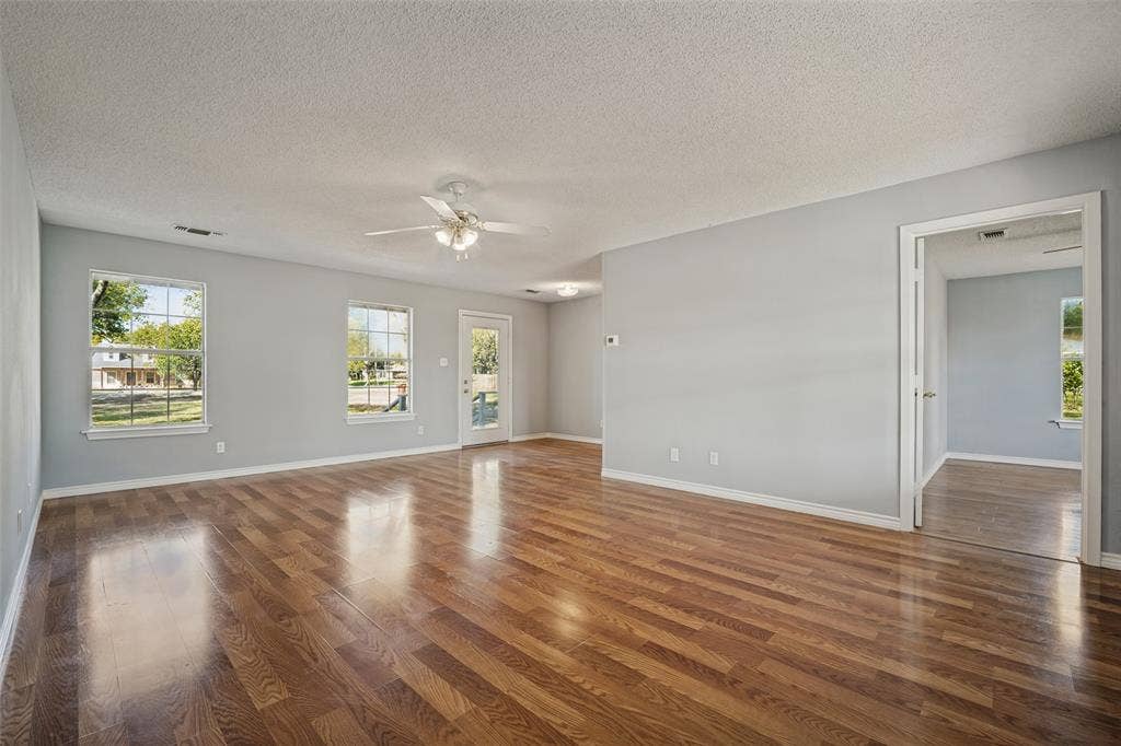 415 S Bell Street, Royse City, TX 75189 Open floor plan featuring wood-finish flooring, multi-pane windows, a central ceiling fan with integrated lighting, and a glass-paneled exterior door