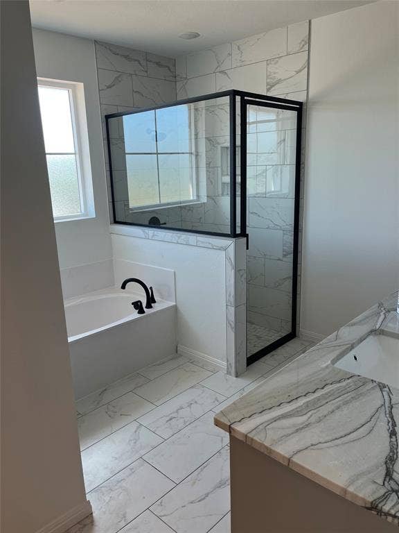 Bathroom featuring a soaking tub, glass-enclosed shower with matte black fixtures, stone-patterned tile flooring, and a stone countertop vanity