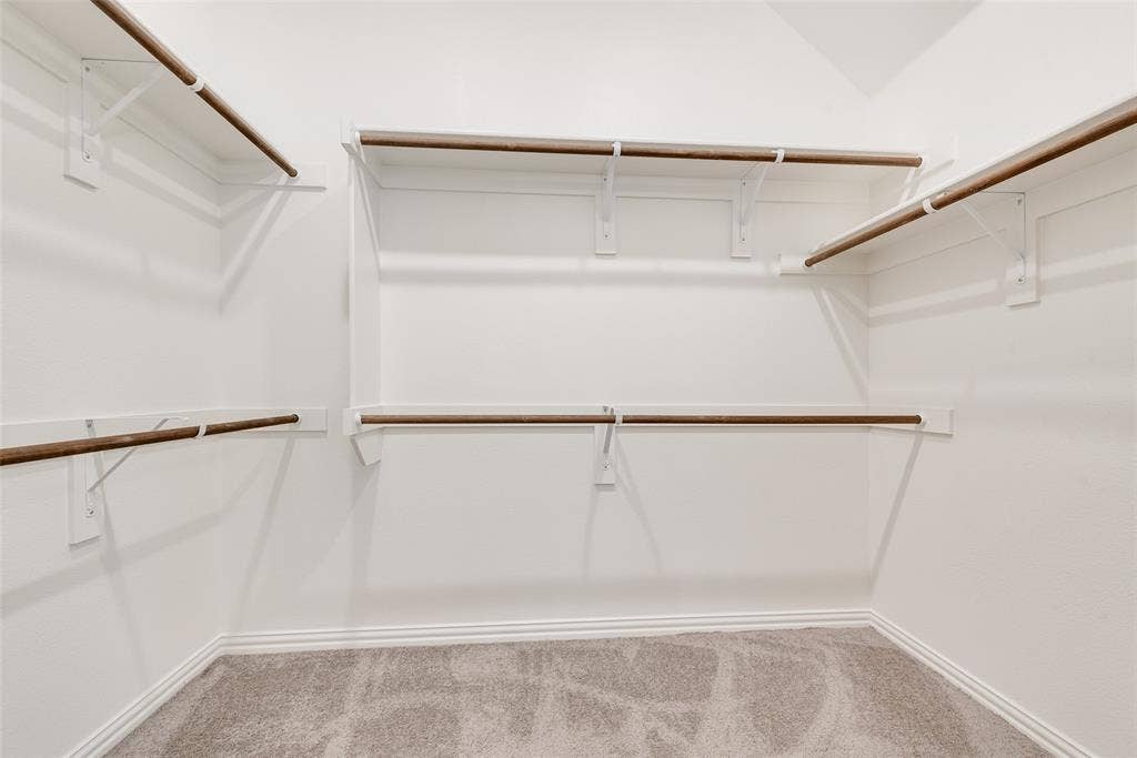 3934 Timberview Street, Midlothian, TX 76065 Walk-in closet featuring multi-level hanging rods, neutral carpeting, and white wall-mounted shelving units