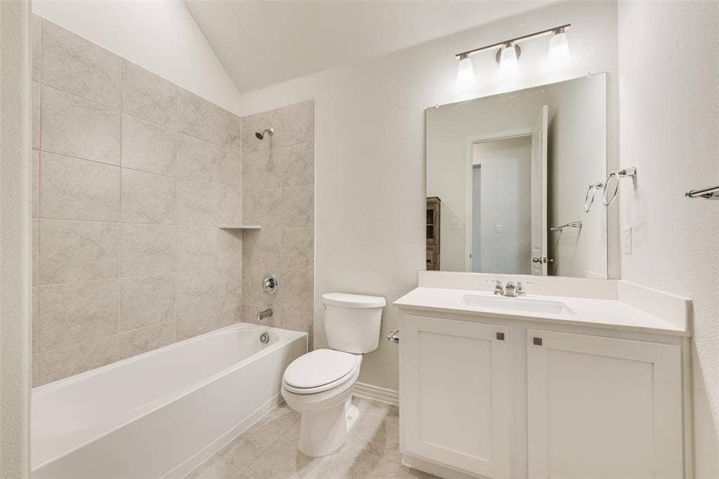 3934 Timberview Street, Midlothian, TX 76065 Full-width vanity with solid-surface countertop and integrated sink, large wall-mounted mirror, three-light fixture, and tiled tub-shower surround with built-in shelf