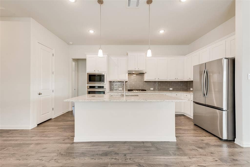 3934 Timberview Street, Midlothian, TX 76065 Kitchen featuring white cabinetry, stone-surface central island, subway tile backsplash, stainless steel appliances, and wood-finish flooring