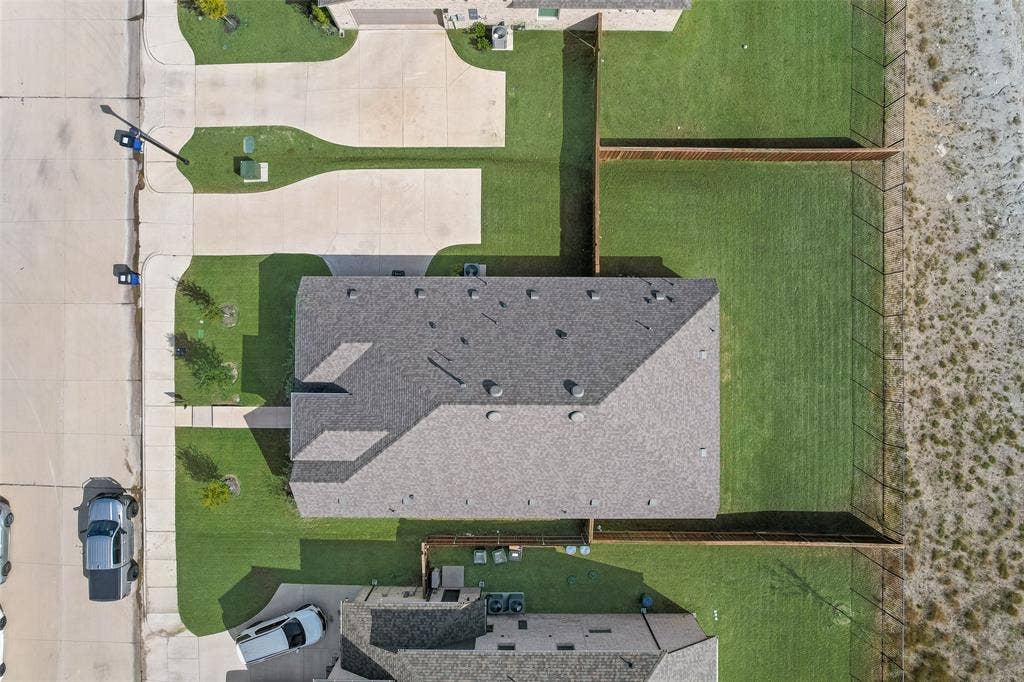 3934 Timberview Street, Midlothian, TX 76065 Aerial perspective featuring a multi-slope composite shingle roof, concrete driveway, and a fenced backyard with lawn