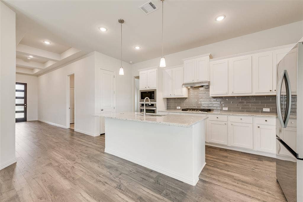 3934 Timberview Street, Midlothian, TX 76065 Kitchen featuring a center island with a stone-finish countertop, white cabinetry, a gray tiled backsplash, built-in stainless steel double ovens, and wood-finish flooring