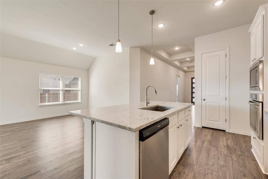 3934 Timberview Street, Midlothian, TX 76065 Kitchen island featuring stone countertops, integrated stainless steel sink, wood-finish flooring, recessed lighting, and built-in stainless steel double wall ovens