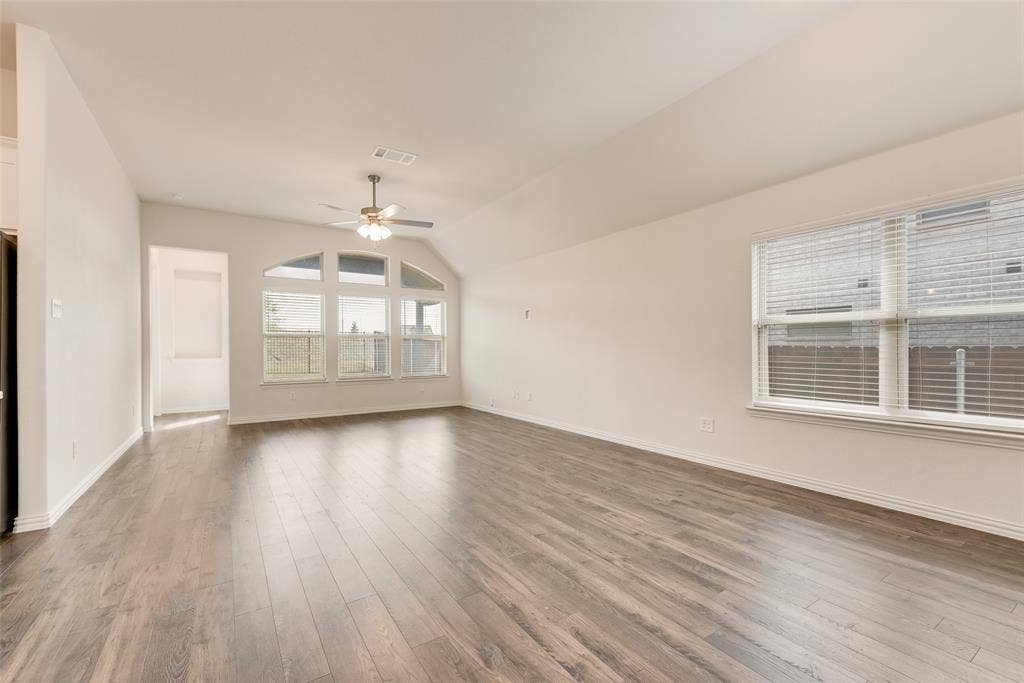 3934 Timberview Street, Midlothian, TX 76065 Open-concept interior featuring wood-finish flooring, vaulted ceilings, a multi-pane arched window, and a ceiling fan with integrated lighting