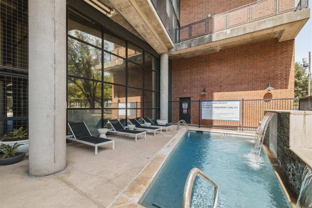 3110 Thomas Avenue, #717, Dallas, TX 75204 Outdoor swimming pool with water features, surrounding lounge area, and full-height windows