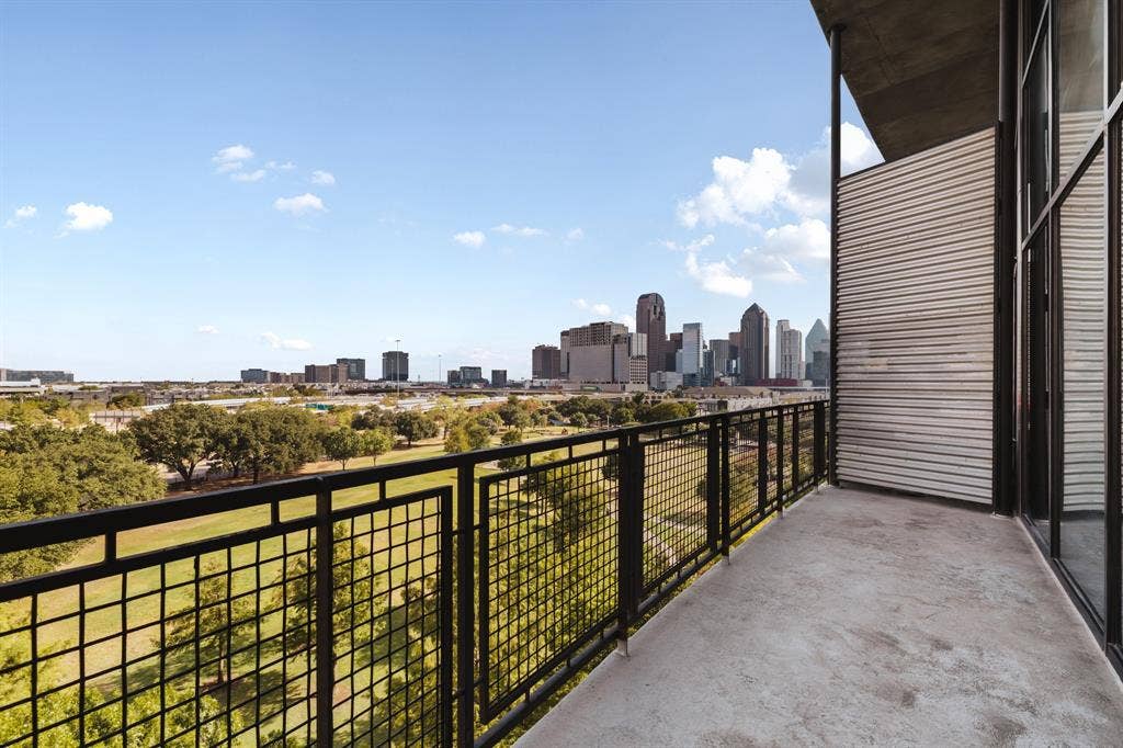 3110 Thomas Avenue, #717, Dallas, TX 75204 Concrete balcony with black metal railings, offering urban skyline and green space scenery