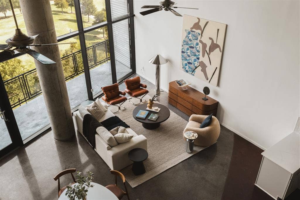 3110 Thomas Avenue, #717, Dallas, TX 75204 Expansive floor-to-ceiling windows, polished concrete flooring, a private balcony with metal railings, a modern ceiling fan, and a built-in wall unit