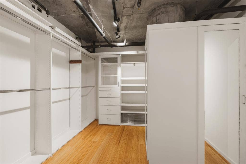 3110 Thomas Avenue, #717, Dallas, TX 75204 Built-in white cabinetry, exposed concrete ceiling, track lighting, and wood-finish flooring