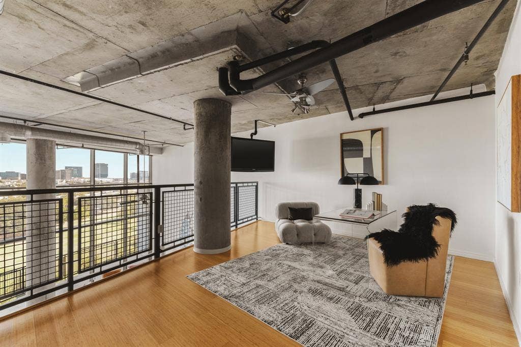 3110 Thomas Avenue, #717, Dallas, TX 75204 Exposed concrete ceiling with industrial piping, wood-finish flooring, full-height windows, and metal grid balcony railing