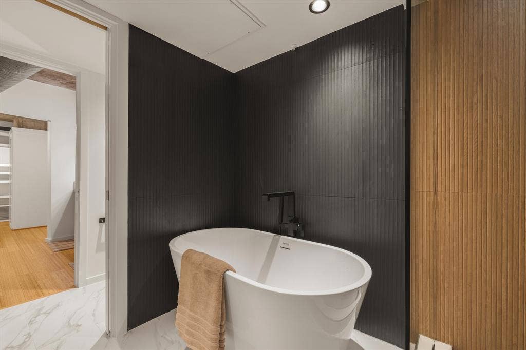 3110 Thomas Avenue, #717, Dallas, TX 75204 Freestanding soaking tub with matte black fixtures, set against a dark fluted accent wall