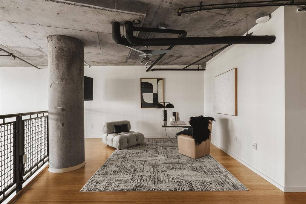 3110 Thomas Avenue, #717, Dallas, TX 75204 Exposed concrete ceiling, industrial-style black piping, concrete structural column, light wood-finish flooring, and white painted walls