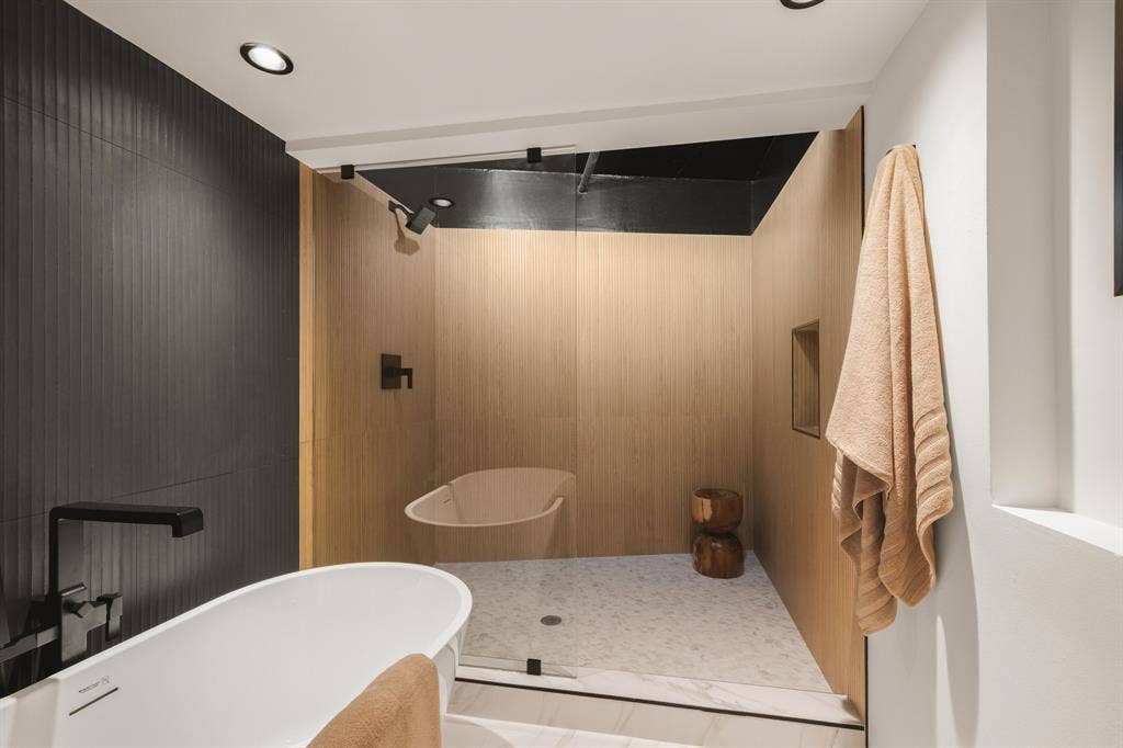 3110 Thomas Avenue, #717, Dallas, TX 75204 Freestanding soaking tub with a wall-mounted matte black faucet, walk-in shower with light wood-finish walls, glass enclosure, and recessed lighting