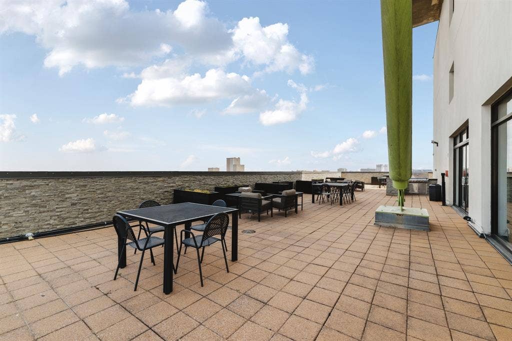 3110 Thomas Avenue, #717, Dallas, TX 75204 Expansive outdoor terrace featuring paver flooring, a perimeter wall, and a building exterior with large window openings