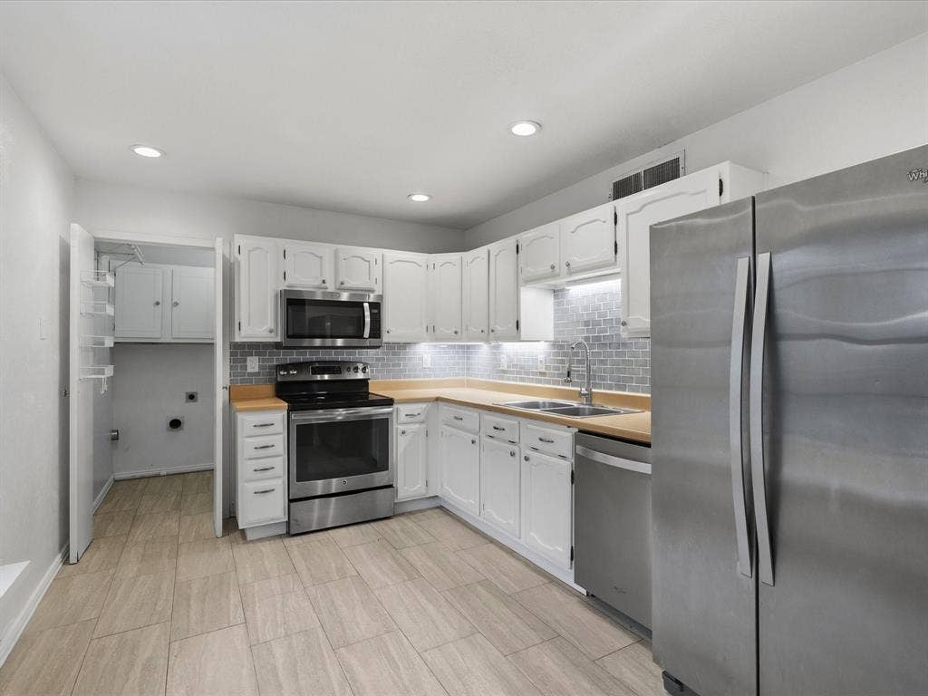 Kitchen featuring white cabinetry, stainless steel appliances, subway tile backsplash, wood-finish flooring, and recessed lighting