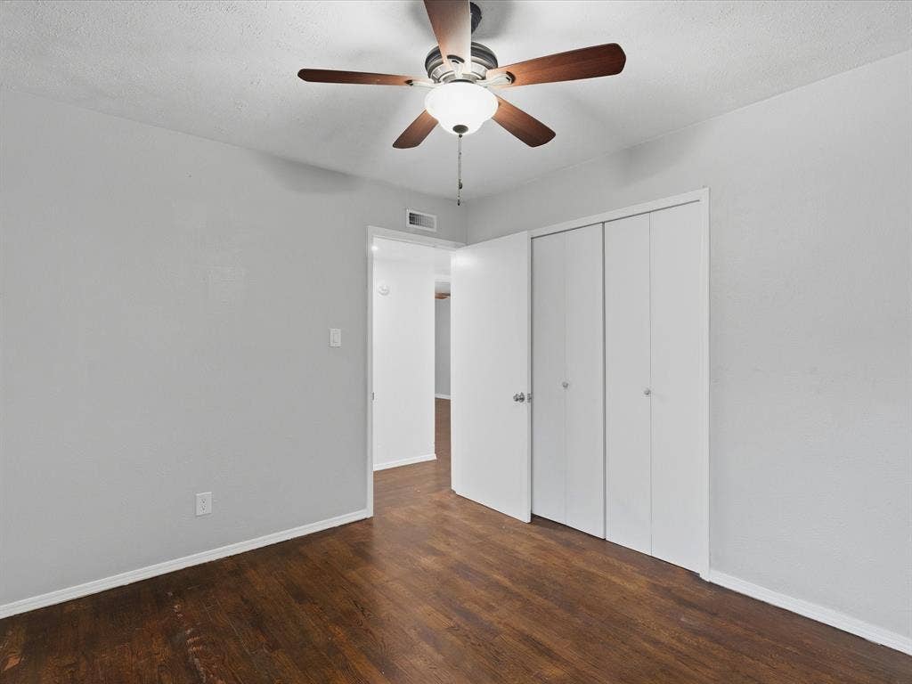 Interior room featuring wood-finish flooring, a ceiling fan with integrated lighting, and a double-door closet