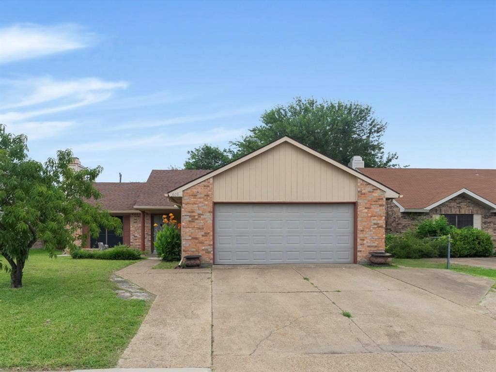 Exterior featuring a multi-gable roofline, brick and vertical siding facade, attached two-car garage, and concrete driveway