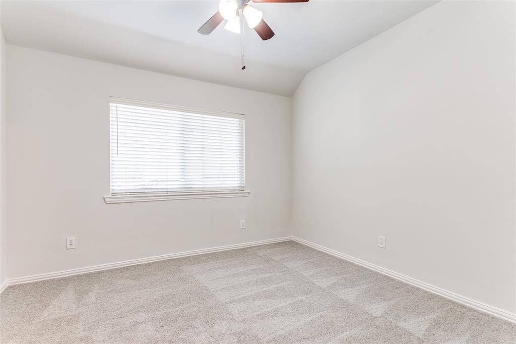 1214 Saint Regis Drive, Irving, TX 75038 Neutral wall tones, carpeting, vaulted ceiling, ceiling fan with light fixture, and horizontal window blinds