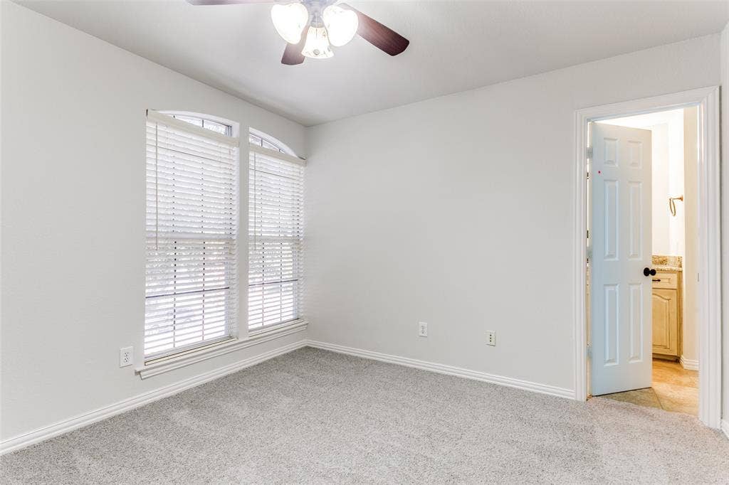 1214 Saint Regis Drive, Irving, TX 75038 Neutral interior space featuring arched windows, wall-to-wall carpeting, and a ceiling fan with integrated lighting