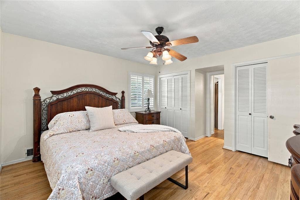 Wood-finish flooring, ceiling fan with integrated lighting, dual louvered-door closets, and plantation shutters