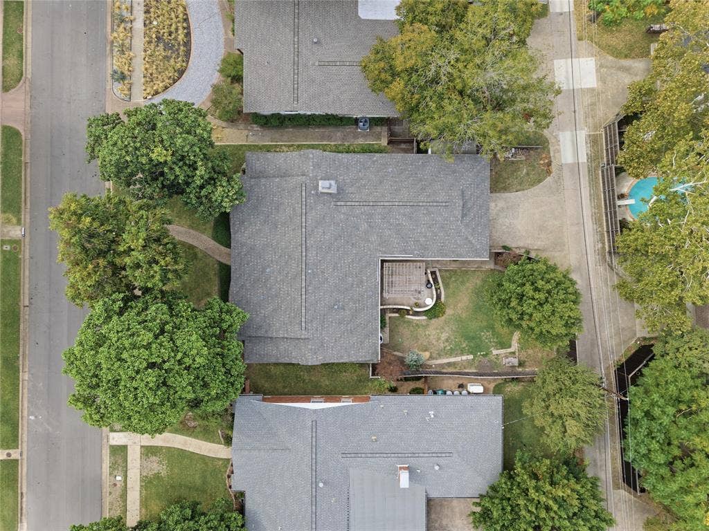 Aerial perspective of a property featuring mature trees, a private backyard with a pergola, and hardscaped exterior grounds