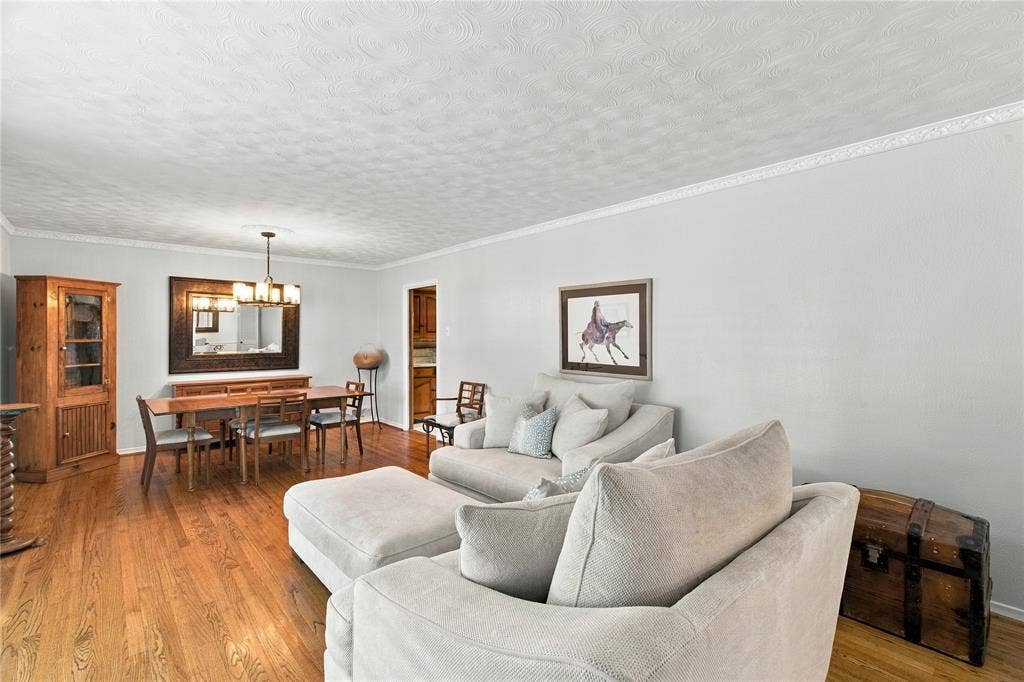 Wood-finish flooring, textured ceiling, crown molding, and a multi-light hanging chandelier