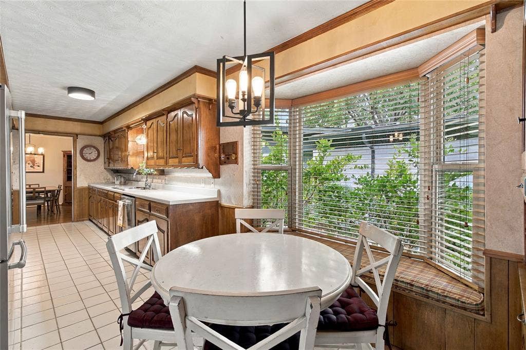 Kitchen featuring wood cabinetry, solid surface countertops, tile flooring, and a bay window with a built-in window seat