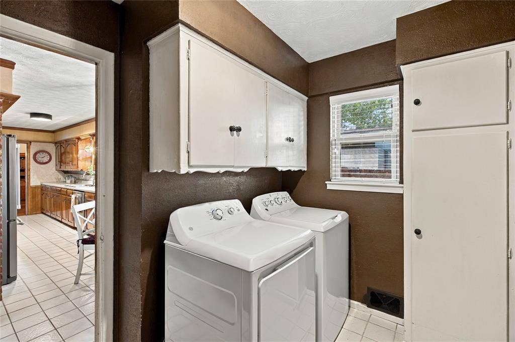 Laundry area featuring wall-mounted cabinetry, floor-to-ceiling storage, and a window with horizontal blinds