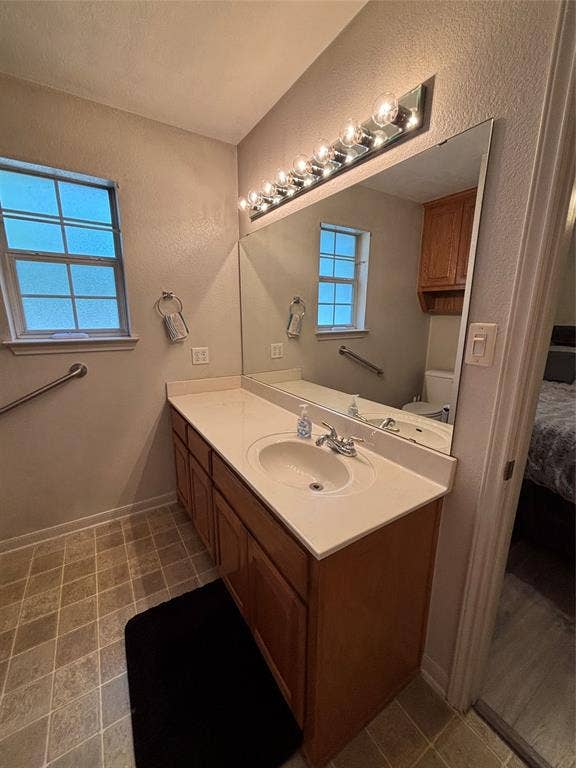 1 Mulberry Court, Morgans Point Resort, TX 76513 Primary bathroom vanity featuring wood-finish cabinetry, a solid-surface countertop with an integrated basin, a full-width wall mirror, and multi-bulb lighting.