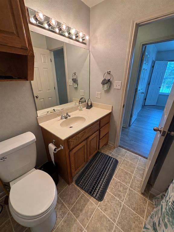 1 Mulberry Court, Morgans Point Resort, TX 76513 Vanity with wood-finish cabinetry, solid-surface countertop, integrated basin, and multi-bulb vanity lighting