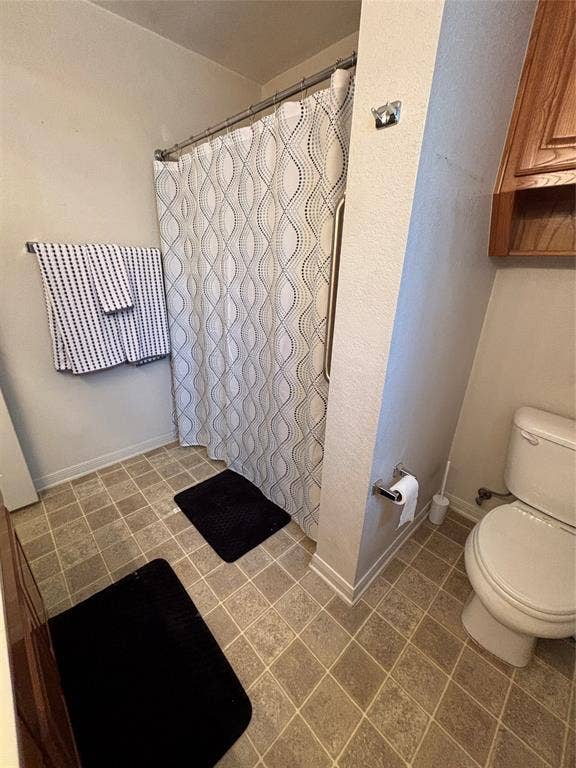 1 Mulberry Court, Morgans Point Resort, TX 76513 Primary bathroom featuring tile flooring, a built-in wood-finish upper cabinet, a combination tub and shower with a metal grab bar, and a wall-mounted towel bar
