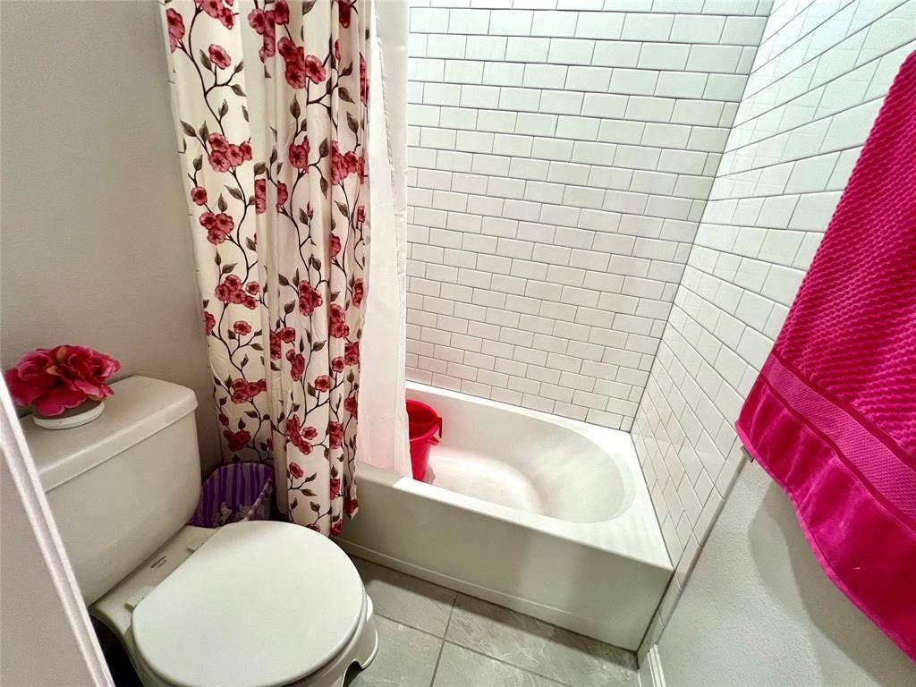 2707 Woodland Court, Wylie, TX 75098 Bathroom featuring shower / bathtub combination with curtain, tile patterned floors, and toilet