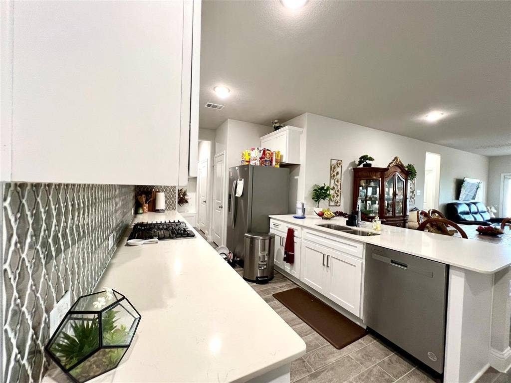 2707 Woodland Court, Wylie, TX 75098 Kitchen with tasteful backsplash, sink, white cabinetry, kitchen peninsula, and stainless steel appliances