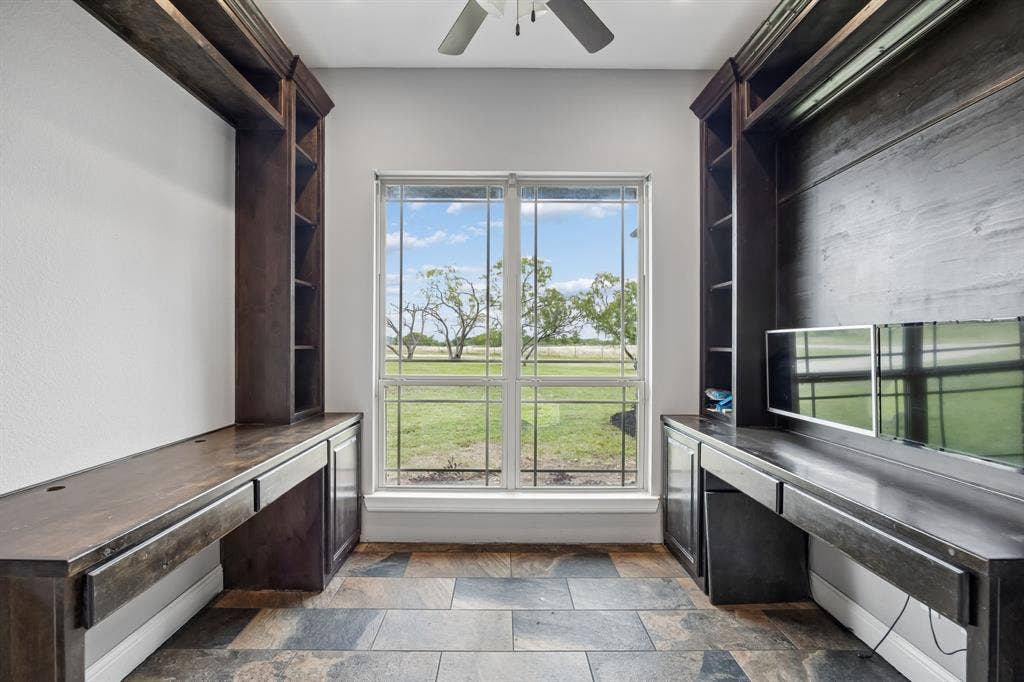 Custom built-in wood cabinetry with integrated shelving and desk surfaces, tile flooring, and a large dual-pane window