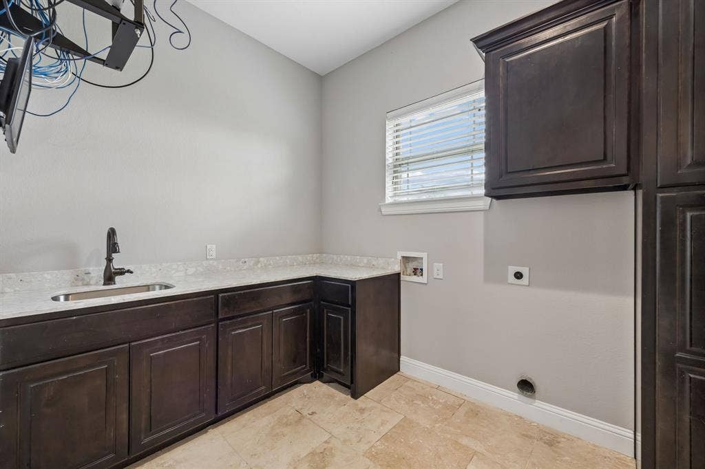 Dark wood cabinetry, stone-finish countertops, drop-in sink with a high-arch faucet, and tile flooring
