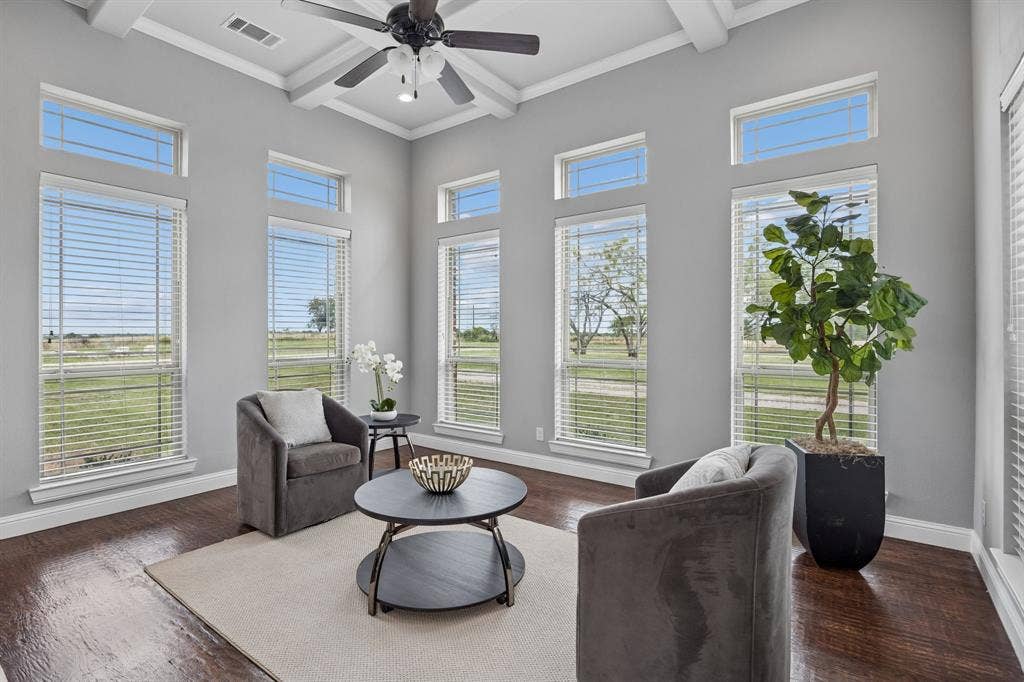 Coffered ceiling with a center-mounted ceiling fan, wood-finish flooring, and expansive windows featuring transom detailing