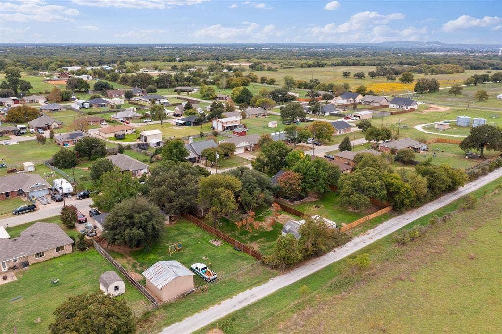 4043 Country Meadows Circle, Granbury, TX 76049 Aerial perspective featuring expansive acreage, mature tree canopy, fenced perimeter, and detached metal storage structure