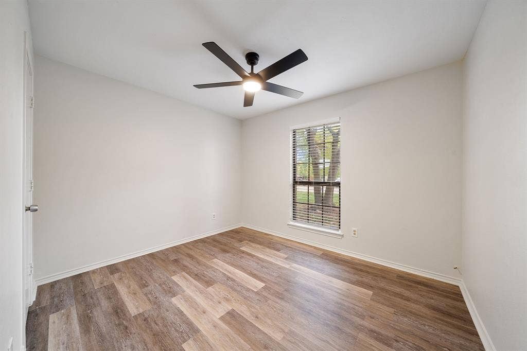 4043 Country Meadows Circle, Granbury, TX 76049 Room featuring wood-finish flooring, a matte black multi-blade ceiling fan with integrated lighting, and a single-pane window