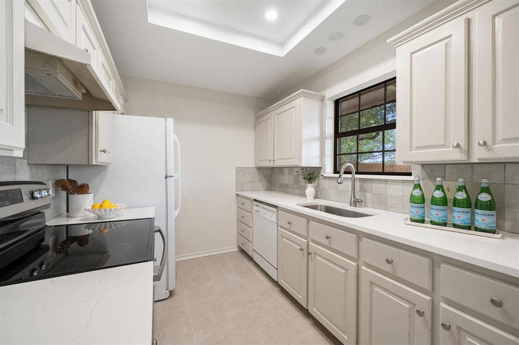 4043 Country Meadows Circle, Granbury, TX 76049 Kitchen featuring white shaker-style cabinetry, solid-surface countertops, a tiled backsplash, and an undermount stainless steel sink with a gooseneck faucet