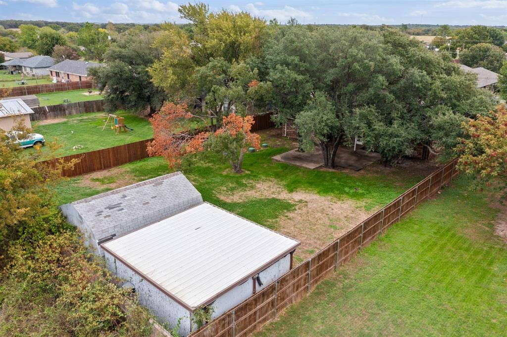 4043 Country Meadows Circle, Granbury, TX 76049 Expansive backyard featuring mature shade trees, a detached storage building with a metal roof, and wood-style privacy fencing