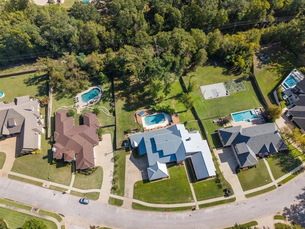 1997 Hollystone Drive, Tyler, TX 75703 Aerial perspective featuring a multi-gabled residence with a metallic roof, rear swimming pool, concrete driveway, and expansive grass lawn