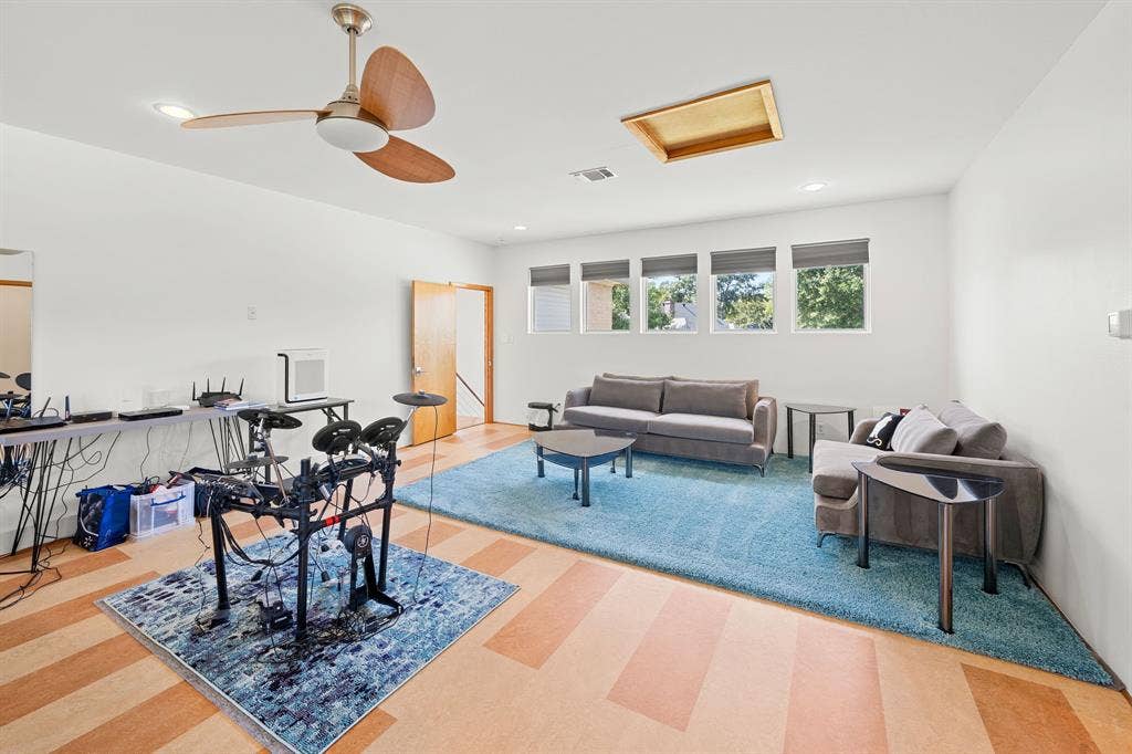 1997 Hollystone Drive, Tyler, TX 75703 Expansive room featuring multi-tonal wood-finish flooring, recessed lighting, a ceiling fan, and a series of five rectangular windows with fitted shades