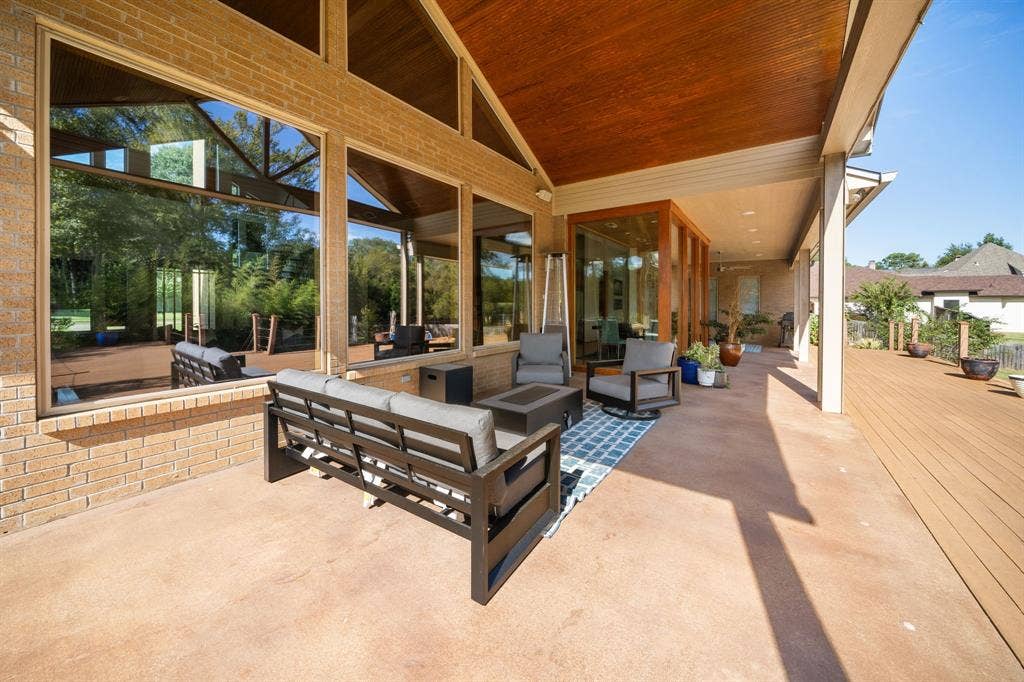 1997 Hollystone Drive, Tyler, TX 75703 Covered patio featuring a high, wood-planked ceiling, expansive floor-to-ceiling windows, brick exterior walls, and a wood-finish deck