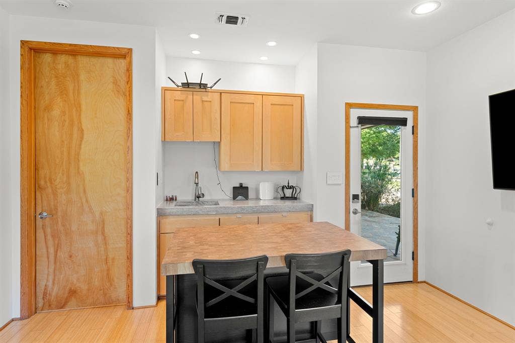 1997 Hollystone Drive, Tyler, TX 75703 Custom kitchenette featuring light wood cabinetry, stone-surface countertop with an integrated sink, recessed lighting, and wood-finish flooring