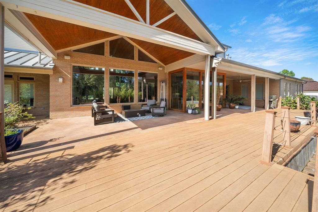 1997 Hollystone Drive, Tyler, TX 75703 Expansive wood-finish deck featuring a covered patio area, vaulted ceilings with wood inlay, large picture windows, and cable railing