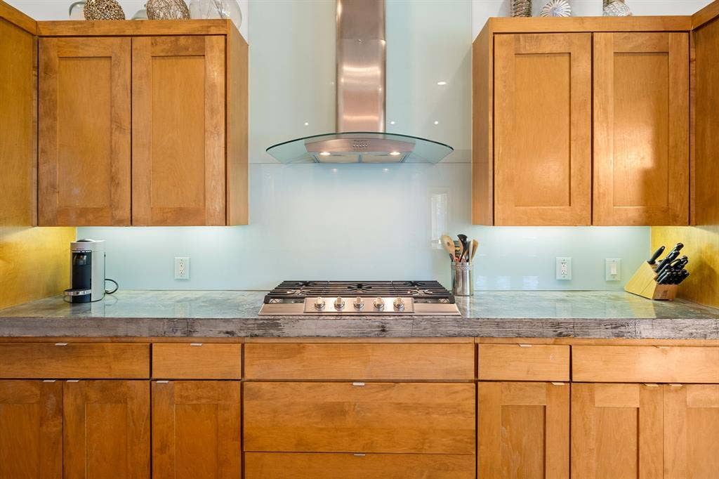 1997 Hollystone Drive, Tyler, TX 75703 Custom cabinetry with shaker-style doors, stone countertop, glass backsplash, stainless steel gas cooktop, and glass canopy range hood