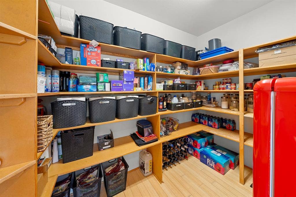 1997 Hollystone Drive, Tyler, TX 75703 Walk-in pantry featuring extensive wrap-around wooden shelving, light-toned wood-finish flooring, and a dedicated built-in wine rack