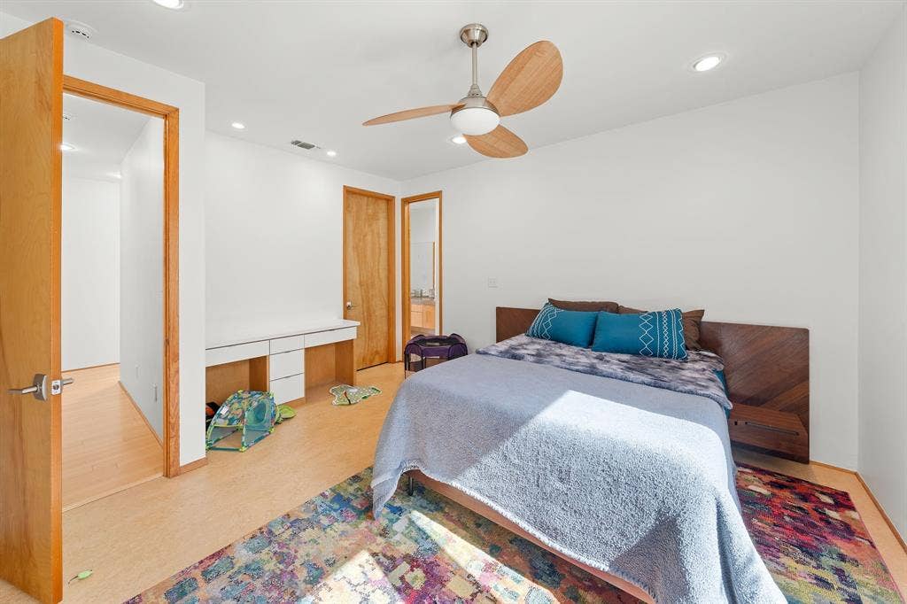 1997 Hollystone Drive, Tyler, TX 75703 Room featuring wood-finish flooring, recessed lighting, a modern ceiling fan, a built-in white desk with drawer storage, and a custom wood-panel headboard