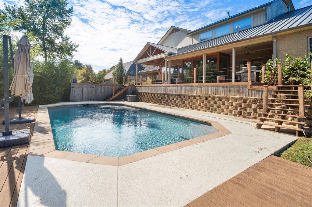 1997 Hollystone Drive, Tyler, TX 75703 Inground swimming pool with concrete decking, tiered retaining wall, elevated wooden deck, and covered patio space
